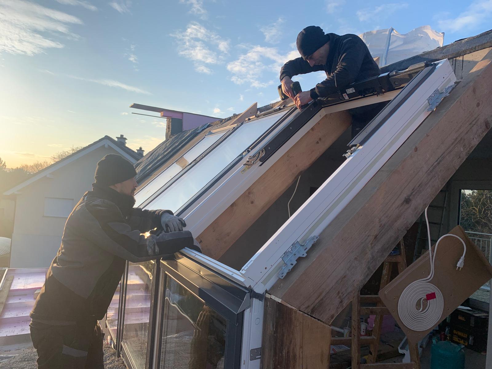 Zwei Monteure bei der Dachfenstermontage im Morgenlicht