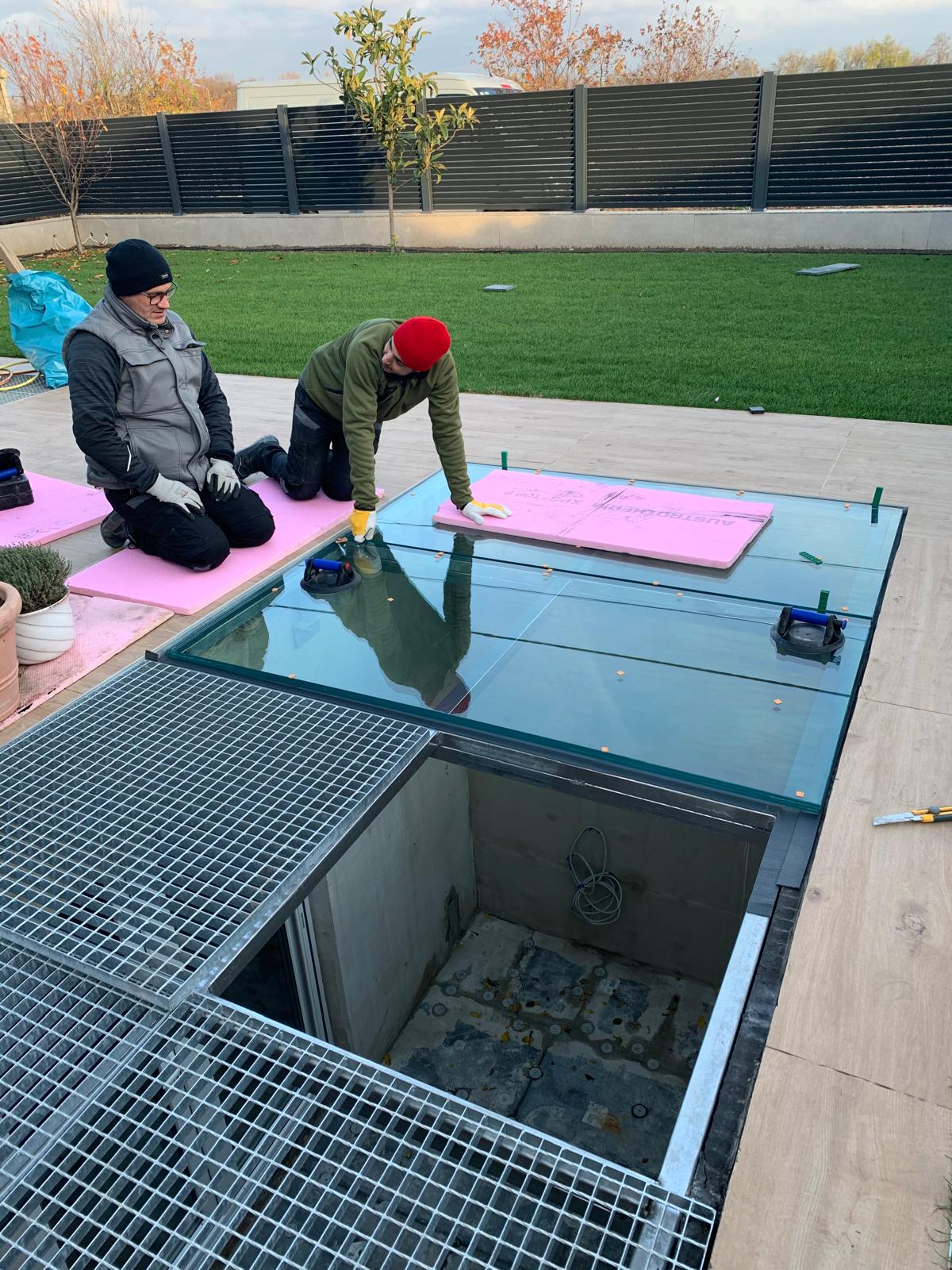 Monteur vermisst und montiert ein begehbares Glasbodenelement auf einer Terrasse