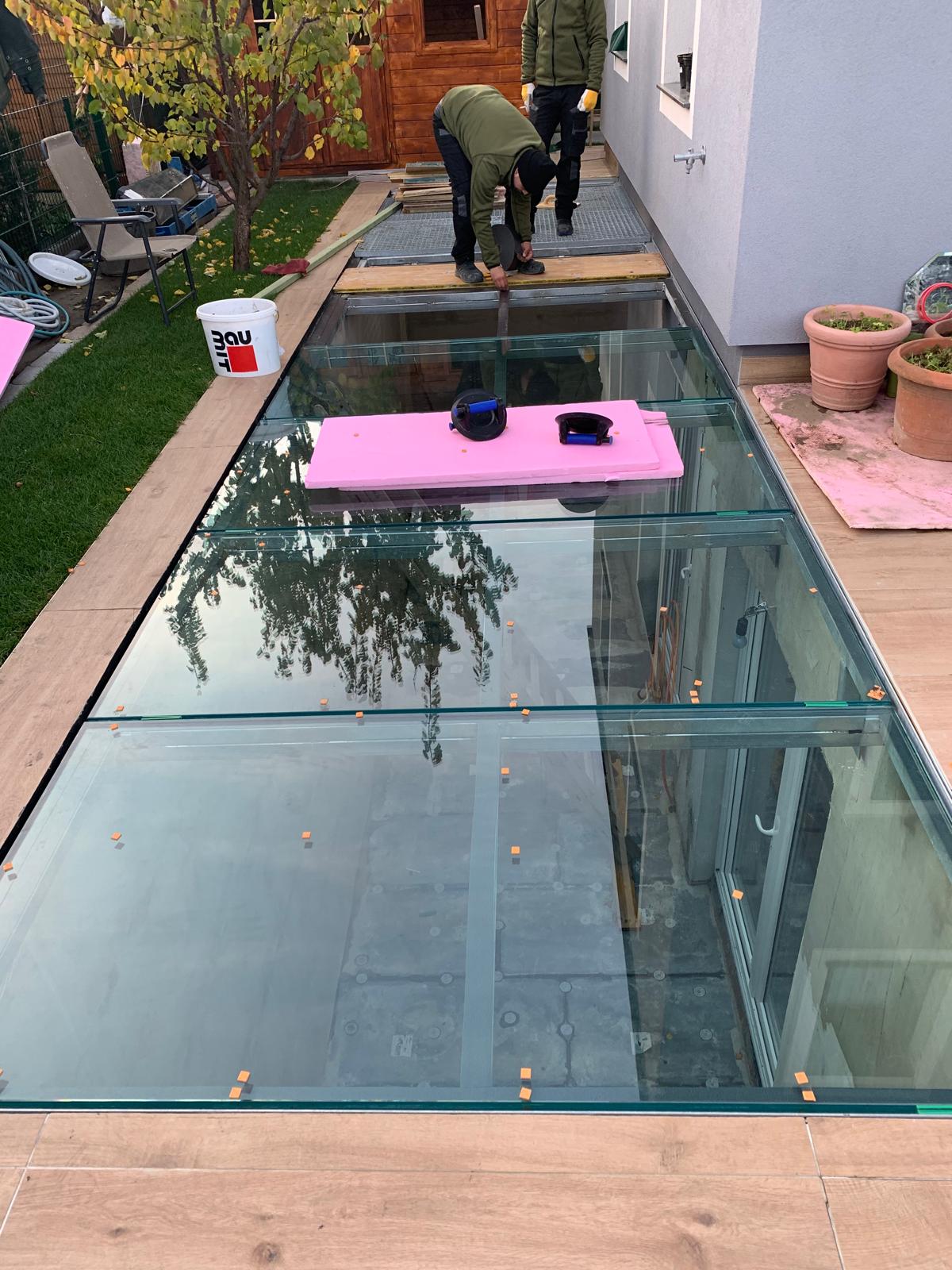 Zwei Monteure bei der Montage eines begehbaren Glasbodens im Garten