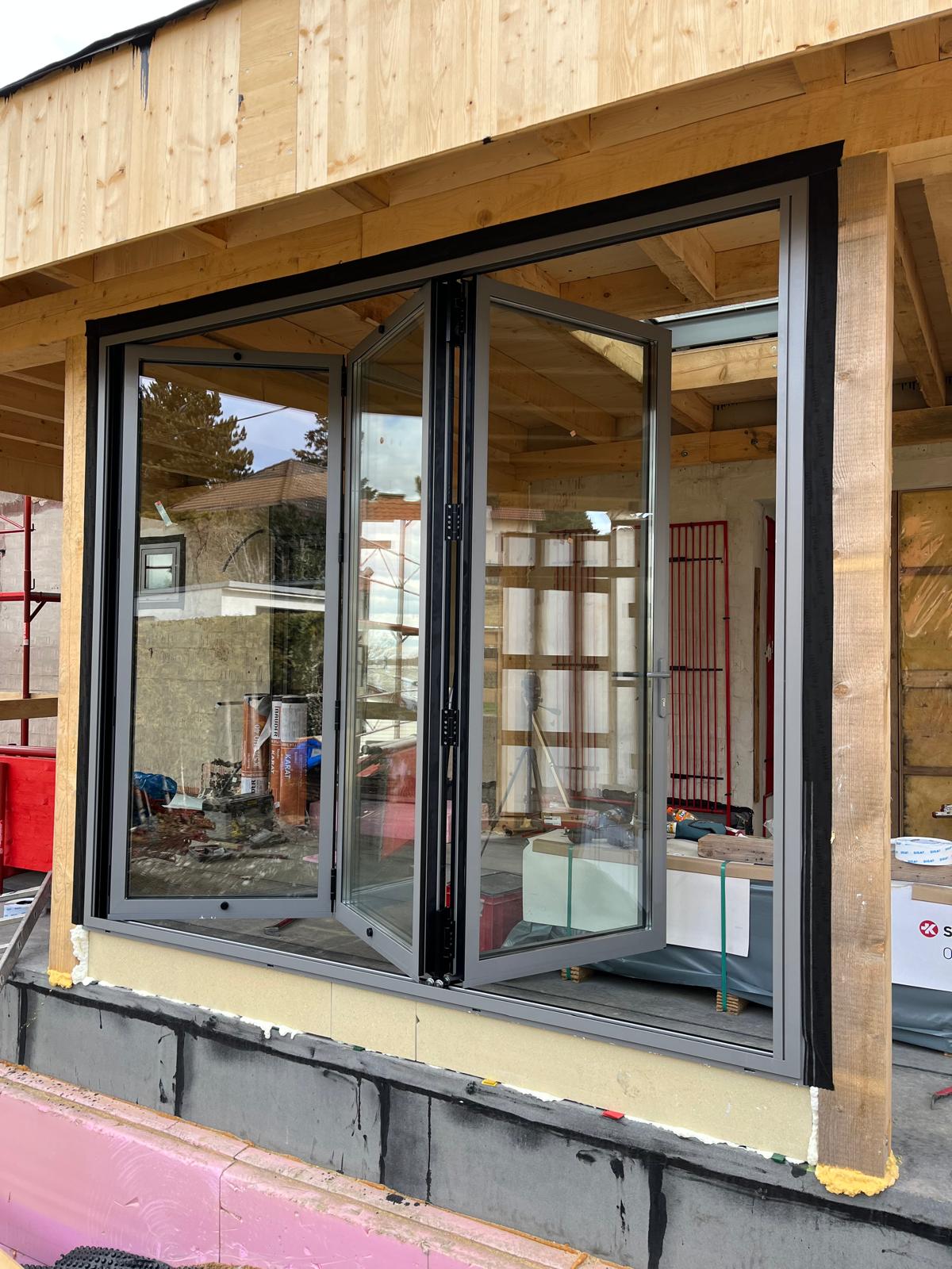 Geöffnete Falt-Schiebetür mit sichtbaren Türflügeln auf einer Baustelle